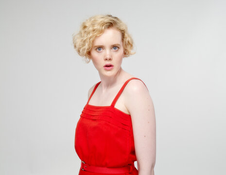 Portrait of astonished young woman in front of grey background