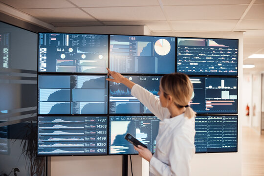 Medical professional analyzing AI data on large monitors in clinic