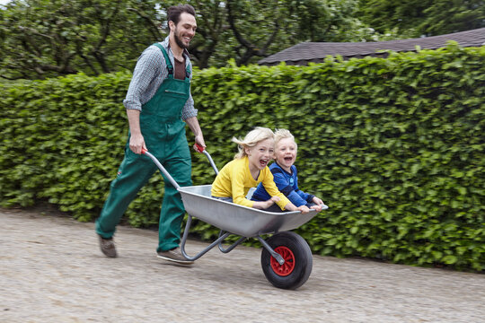 Germany, Cologne, Father carrying son in wheelbarrow, smiling