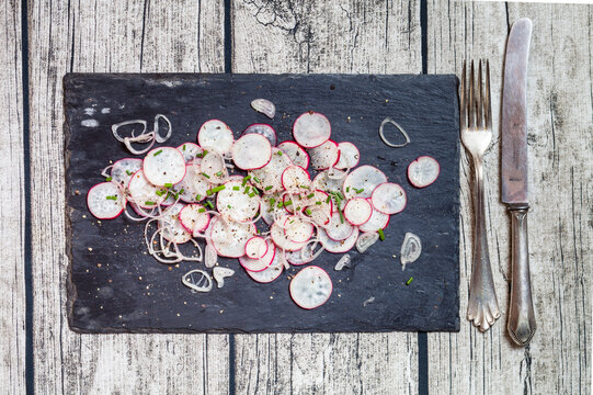 Red radish salad with oniond and cives garnished on slate