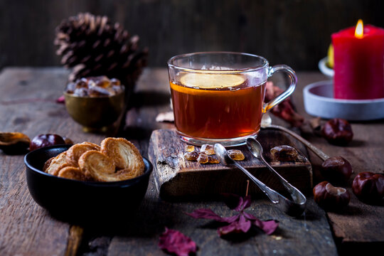 Glass of black tea with slice of lemon and rock sugar on wooden table