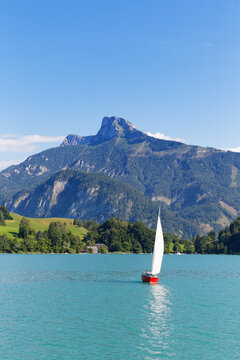 Austria, Upper Austria, Salzkammergut, View of sailing boat in Mondsee Lake, Schafberg in the background