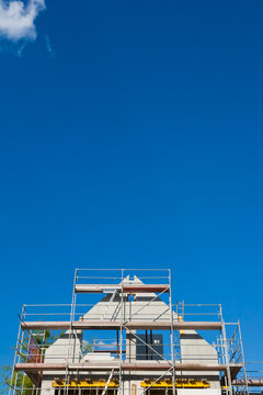 A new house with scaffolding stands under a blue sky in Stuttgart