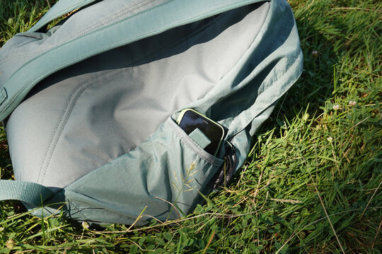 smartphone tucked away in green backpack pocket resting in nature as digital detox concept