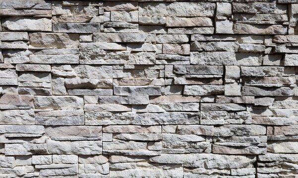 Wall made of reconstructed strips stone with colors ranging from white to beige anf gray. Rustic coating for outdoor or indoor. Background and texture. Full frame.