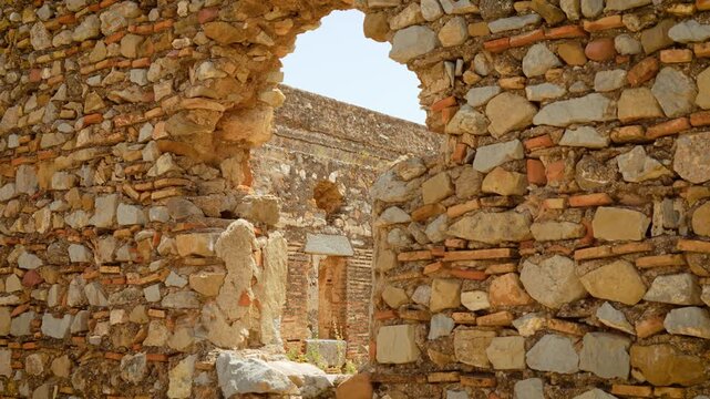 Ancient castle ruins with weathered stone walls and broken window opening. Medieval masonry with bricks under bright sunlight. Historic fortress architecture and archaeological heritage site