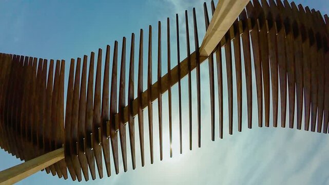 Wooden slatted sunshade canopy against bright blue sky with sunlight between beams. Modern outdoor shade structure at seaside promenade. Summer heat protection and coastal architecture