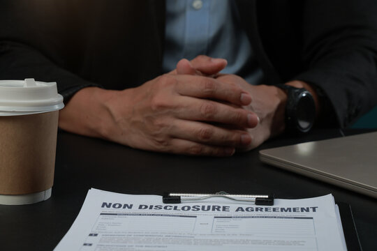 Business document confidentiality agreement hands on desk with coffee cup and laptop for legal meeting in modern office workplace