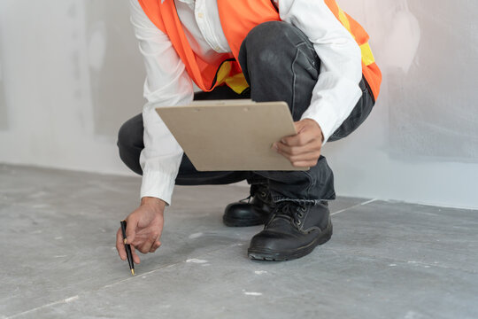 inspector or engineer is inspecting construction and quality assurance check dimension of house by using a tape measurement. Engineers or architects or contactor work to build the house before sell.