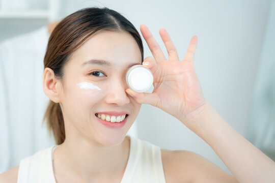 Beautiful Asian woman smile and hold cream for good skin. face of a healthy woman apply cream and makeup. Advertisement skin cream, anti-wrinkle, baby face, whitening, moisturizer, serum