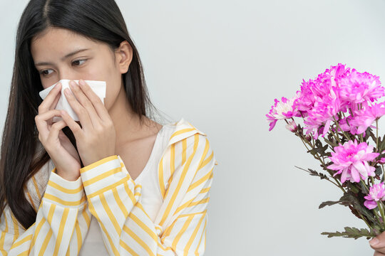 Pollen Allergies, asian young woman sneezing in a handkerchief or blowing in a wipe, allergic to wild spring flowers or blossoms during spring. allergic reaction, respiratory system problems