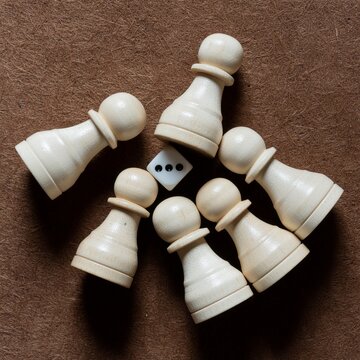 Wooden chess pawns and a single die arranged on a felt surface