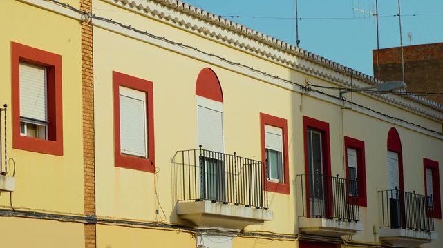 Spanish residential facade with barred balconies and roller shutters. Security railings on apartment windows in urban neighborhood. Anti squatter protection and home security in Spain