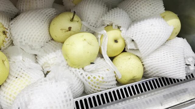 Fresh yellow pears with protective foam net at local market