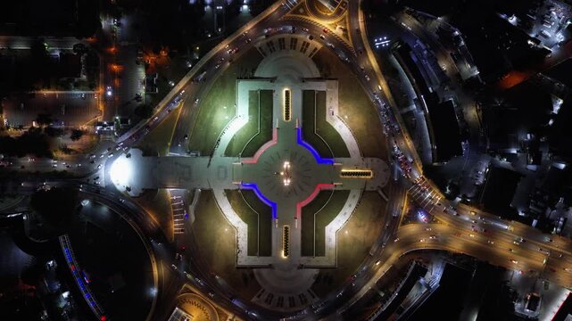 Top down aerial view of Plaza de la Bandera at night in Santo Domingo, Dominican Republic, showing the illuminated plaza, surrounding roads and urban landscape