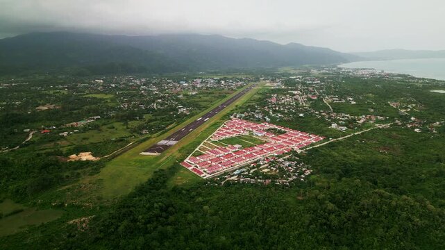 Aerial overview of Virac Airport and nearby subdivision homes surrounded by lush tropical island greenery - Catanduanes, Philippines