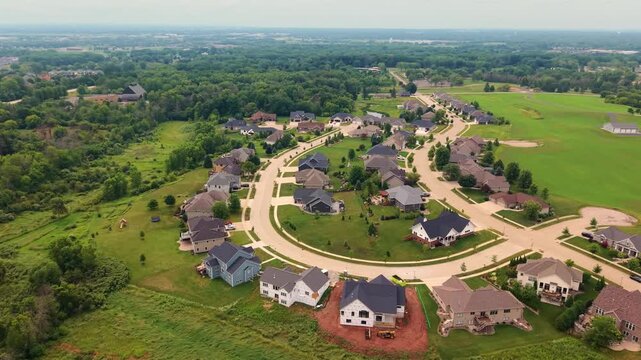 Aerial orbiting establishing shot of curved cul-de-sac loop with detached houses borders open grassland and wooded area Appleton, Wisconsin suburban neighborhood