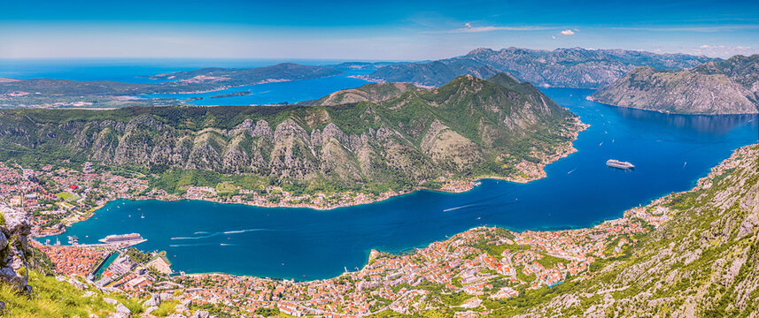Panoramic view of Bay of Kotor, Montenegro, with deep blue water, coastal towns, and surrounding mountains on a clear day