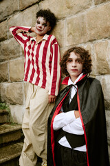 Obraz premium Portrait of diverse teenagers wearing Halloween costumes and makeup while posing outdoors. Image suitable for seasonal marketing campaigns and holiday event promotions, vertical