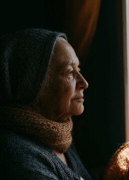 Close-up portrait of an elderly woman's face. she is wearing a gray headscarf and a knitted scarf around her neck.