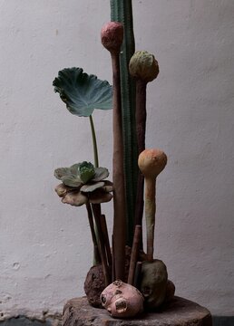 Photograph of a sculpture made from various objects. the sculpture is displayed on a wooden base with a white wall in the background.