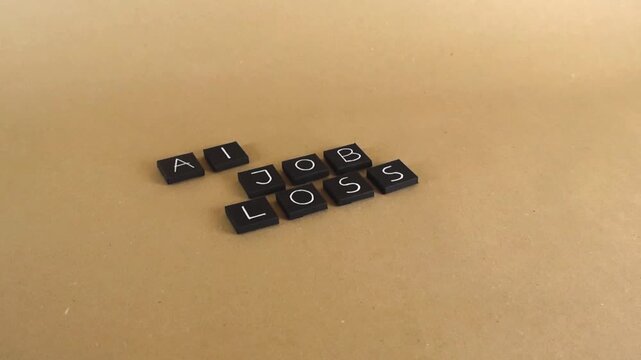 Black letter tiles spelling out AI JOB LOSS on a light brown background, visualizing the concept of unemployment and automation caused by artificial intelligence replacing human labor