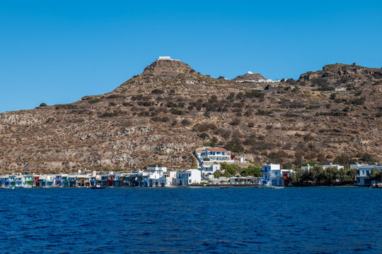 Whitewashed hillside village with blue sea and rocky coastline on Milos