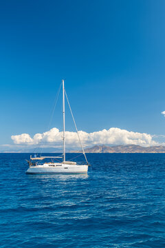 White sailboat on the open sea beneath a bright blue sky near Serifos