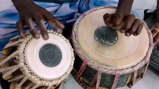 Close-up video of a musician playing a pair of traditional Indian tabla drums. The detailed drumheads, black syahi centre, and hands highlight this classical music, South Asian culture and percussion.