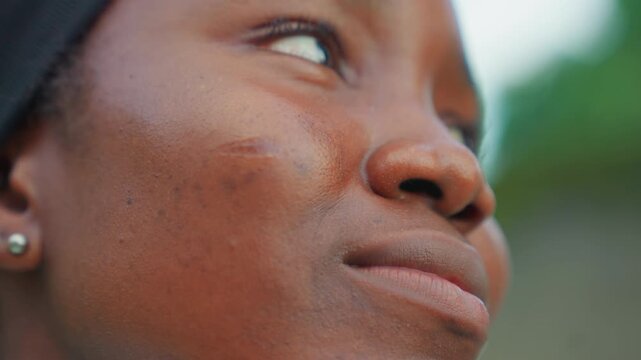 Focused determined gaze. Young woman exudes hopeful confidence. Childlike energy with calm and focused expression. Eyes filled with youthful determination and firm resolve in sky background