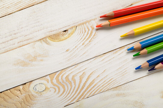 Rainbow colored pencils on light wooden background