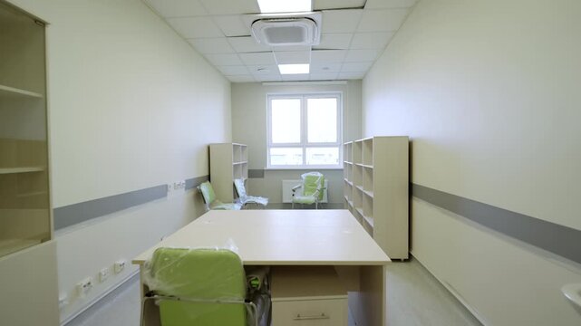 Spacious renovated office room features wooden desk and wrapped green chairs. Radiant natural light fills empty interior through window