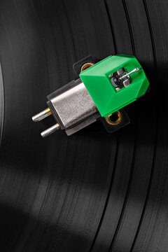 Green phonograph cartridge stylus on vinyl record grooves