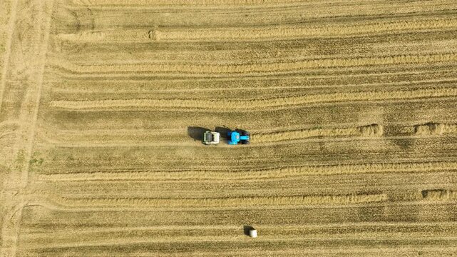 Aerial Top Down View of Tractor and Round Baler Collecting Straw Swath