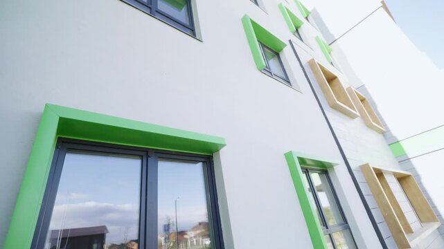 Renovated educational facility shows stylish panels and decorative wooden window boxes. Radiant daytime light enhances neat appearance