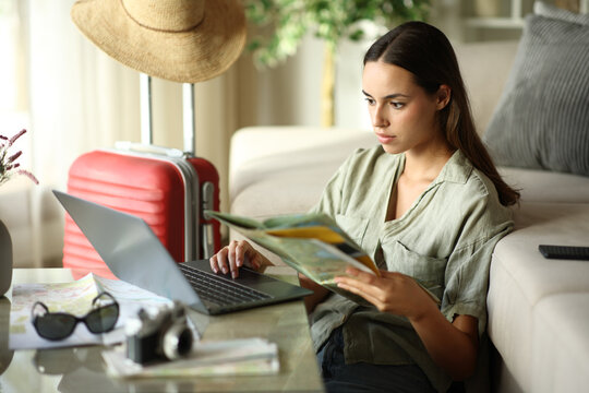 Tourist checking paper guide and laptop on vacation