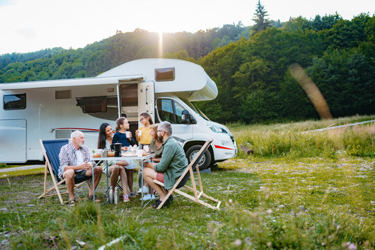 Multigenerational family having picnic dinner during summer caravan vacation.