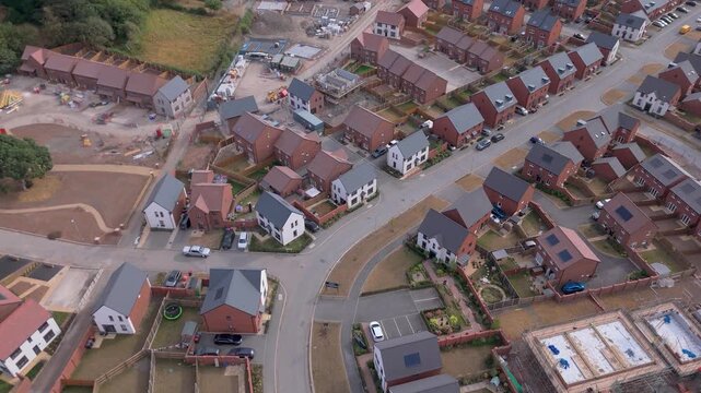 A forward drone view of a brand new housing site with complete and incomplete houses on residential streets