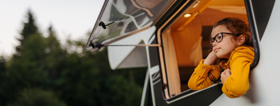 Happy small girl standing by caravan door.