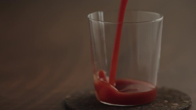 Slow motion pour tomato juice in a glass