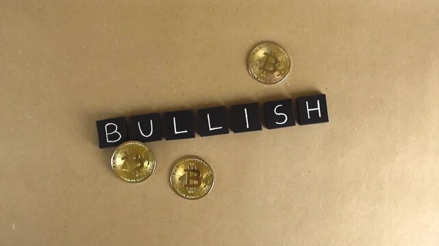 Top down view of golden physical bitcoin coins appearing around the word bullish, spelled out with black letter tiles, conceptualizing a positive and rising cryptocurrency market trend