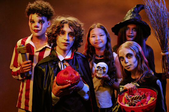 Portrait of diverse teenagers wearing spooky Halloween costumes and holding props. Image suitable for seasonal marketing campaigns and holiday event promotions