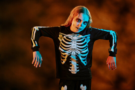 Portrait of Caucasian child wearing skeleton costume and face paint posing for Halloween celebration. Image suitable for seasonal marketing campaigns and holiday event promotions
