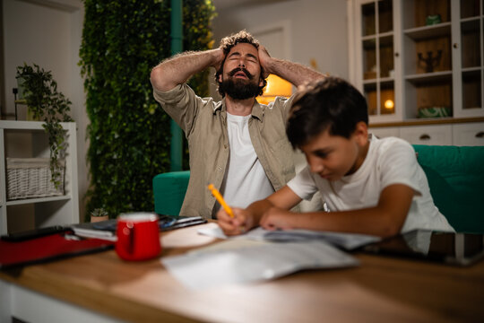 Father feeling frustrated with son doing homework