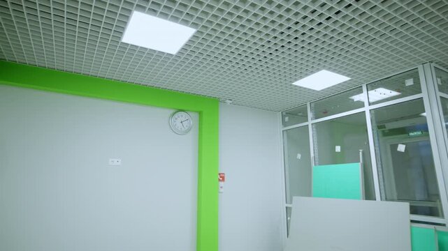 Interior space under renovation features drywall panels on floor and ceiling lights. Construction scene shows worker walking towards exit