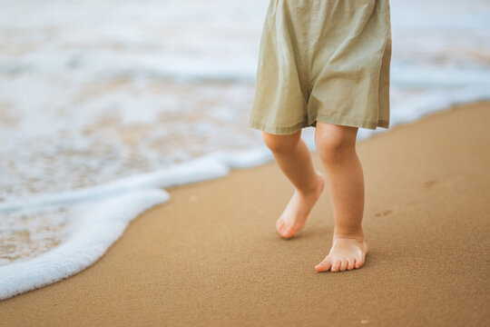Barefoot child walking along sandy beach by the sea, peaceful summer outdoor activity and childhood exploration