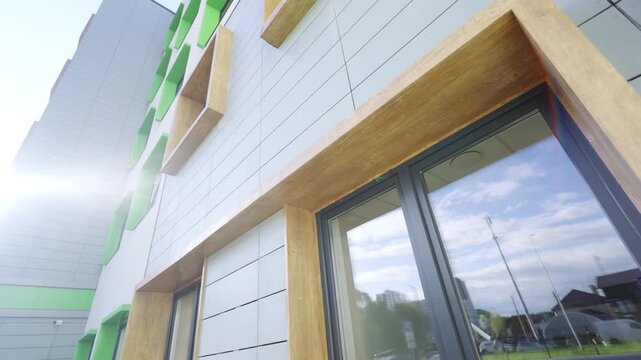Contemporary educational facility demonstrates composite panels and square windows. Radiant daytime light enhances neat exterior design