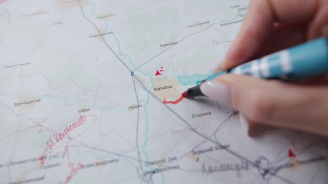 Delicate female hand uses red marker on printed paper map. Thick colored lines circle specific town district territory border line