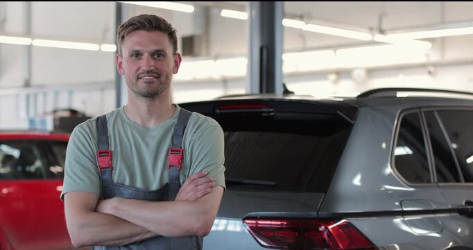 Portrait of a skilled car mechanic in a workshop, with service in the background.