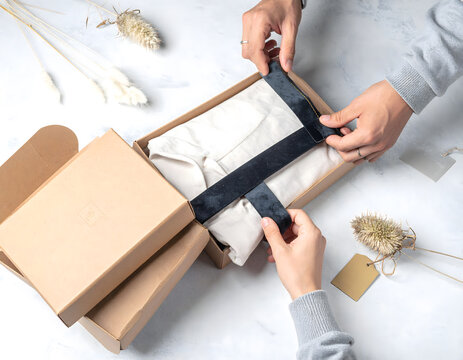 Hands Arranging Velvet Ribbon on Craft Gift Box with Linen Shirt.